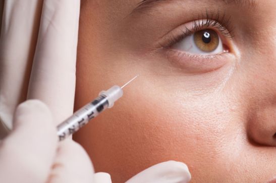 Close up of woman receiving botox injection under eye