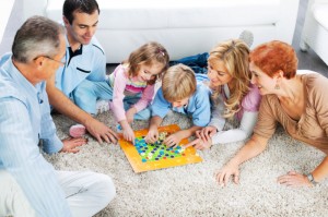 Cheerful extended family playing board game on the floor.